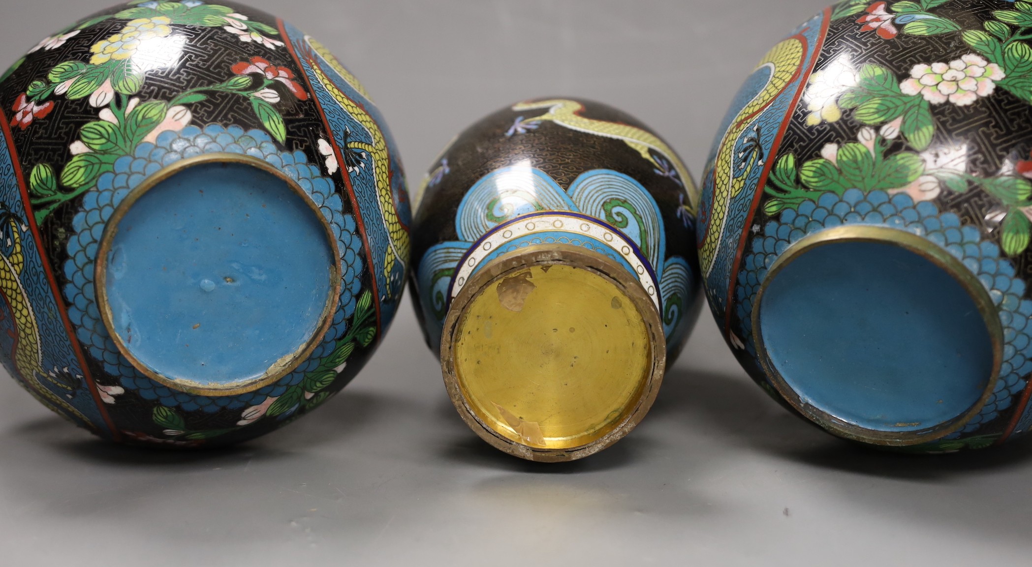 A pair of early 20th century Chinese cloisonné enamel ‘dragon’ jars and covers and a similar vase. Tallest 25.5cm